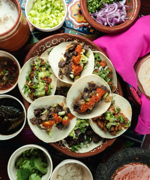 A top view of tasty tortillas with meat and sauce surrounded with ingredients